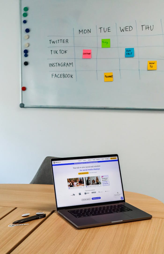 Mastering the First Impression: Your intriguing post title goes here A modern office setup featuring a laptop and a whiteboard schedule for social media platforms.