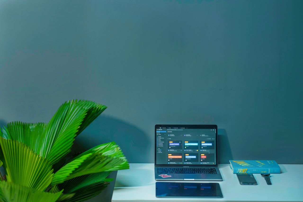Crafting Captivating Headlines: Your awesome post title goes here Sleek office desk setup featuring a laptop, tropical plant, and book in a modern design.