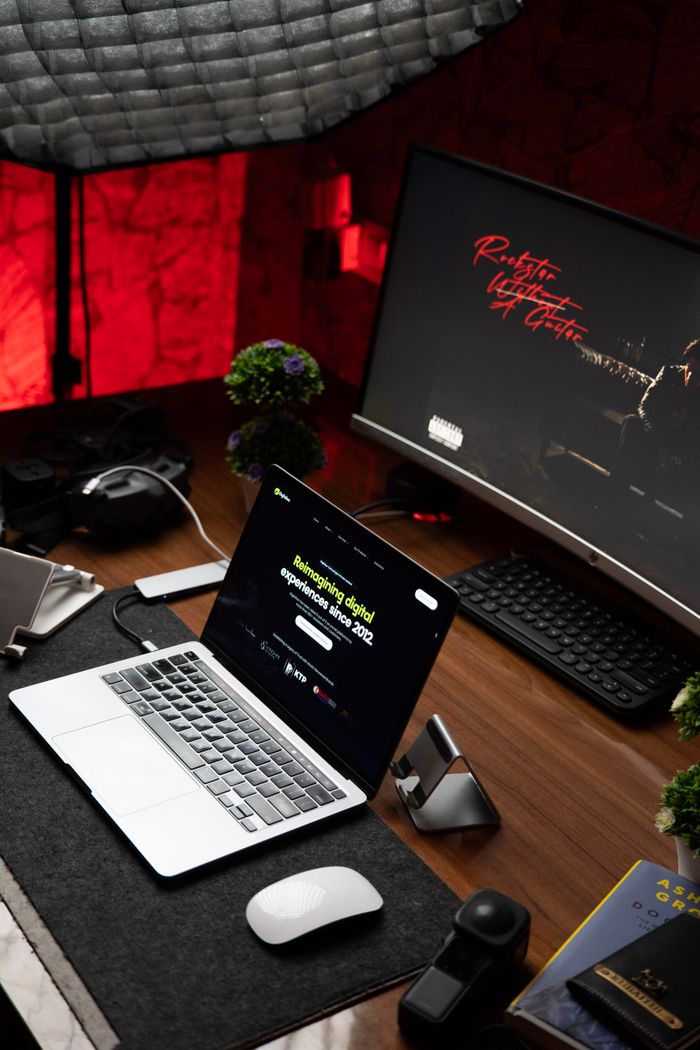 who-we-are Stylish office setup featuring a laptop and monitor on a wooden desk with ambient lighting.
